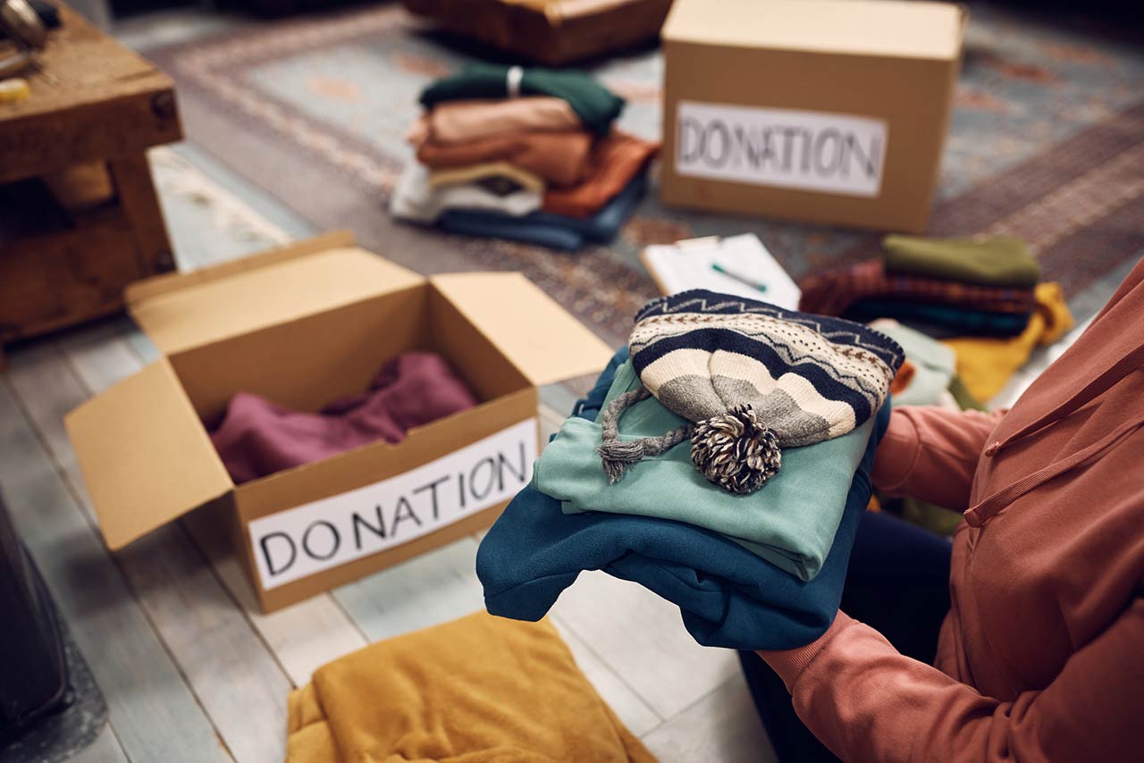 Close-up of woman packing boxes while donating her wardrobe for charity